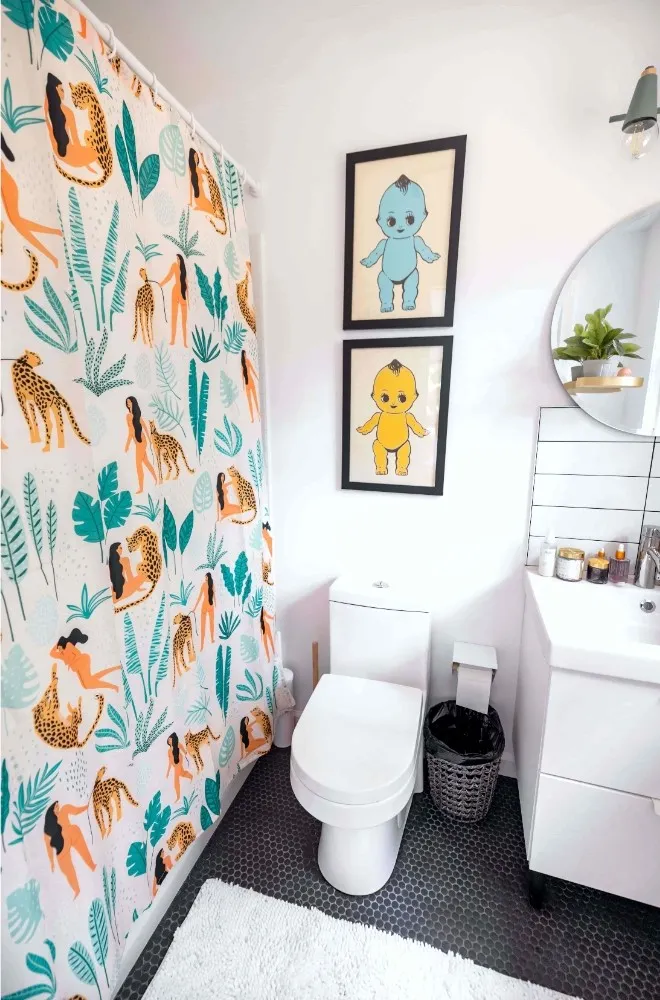 A bathroom with a jungle themed shower curtain that prompts the question: "how often should you change your shower curtain?