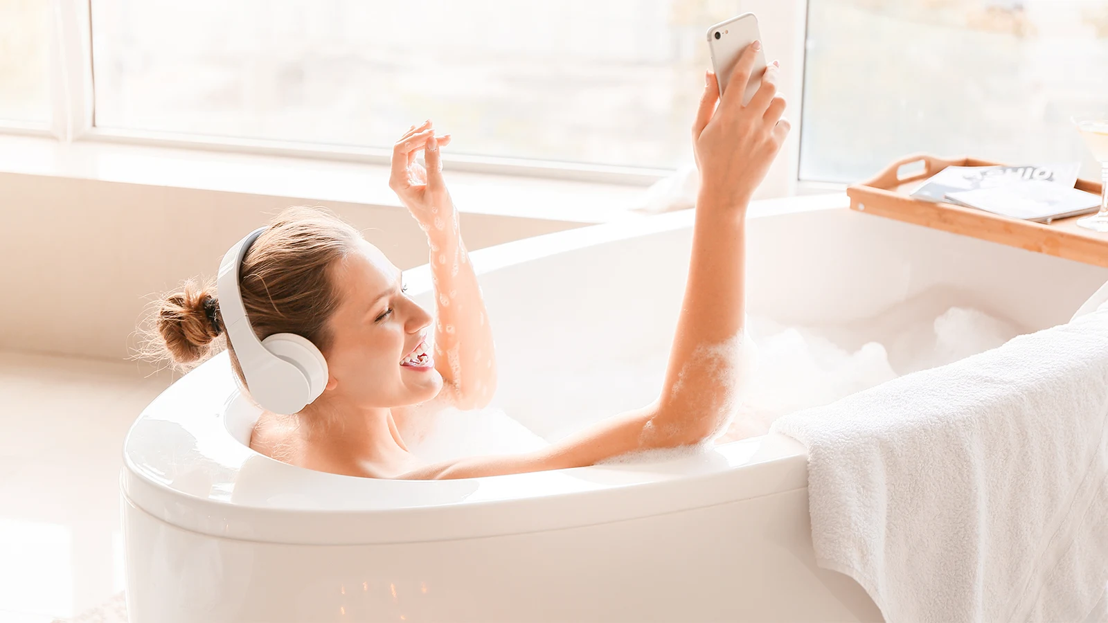 A woman is taking a bath while listening to music.