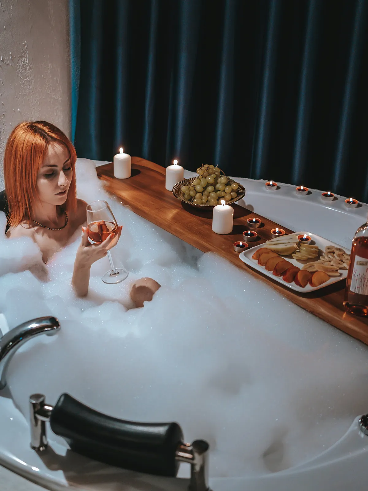 A woman is sitting in a bubble bath with a glass of wine.