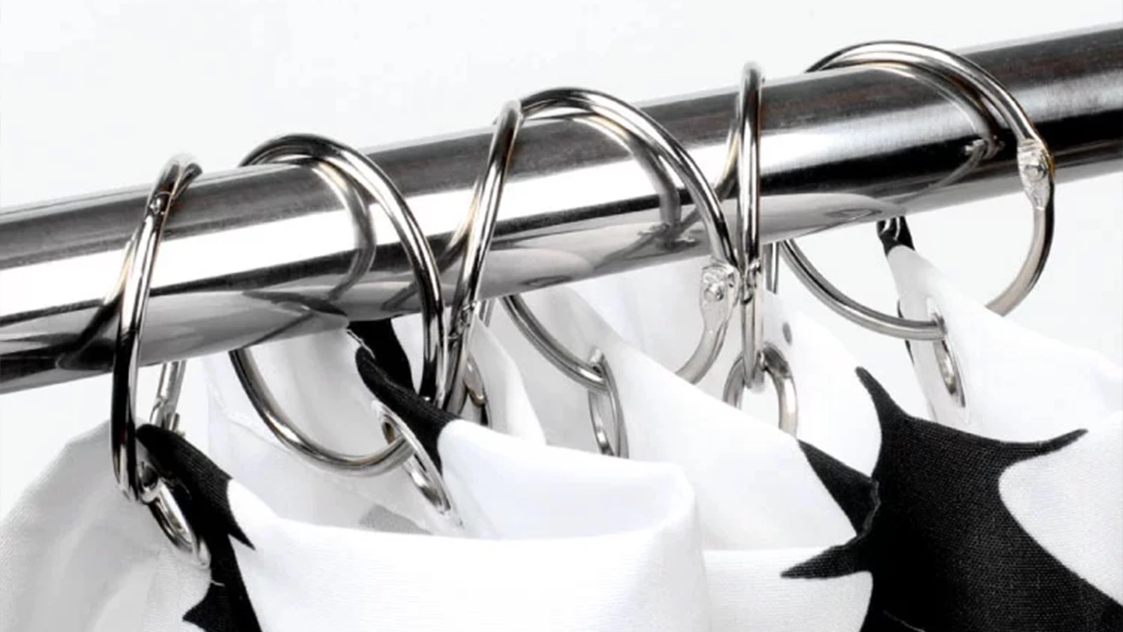 Types of Shower Curtain Hooks: A black and white shower curtain hangs on a metal rod.