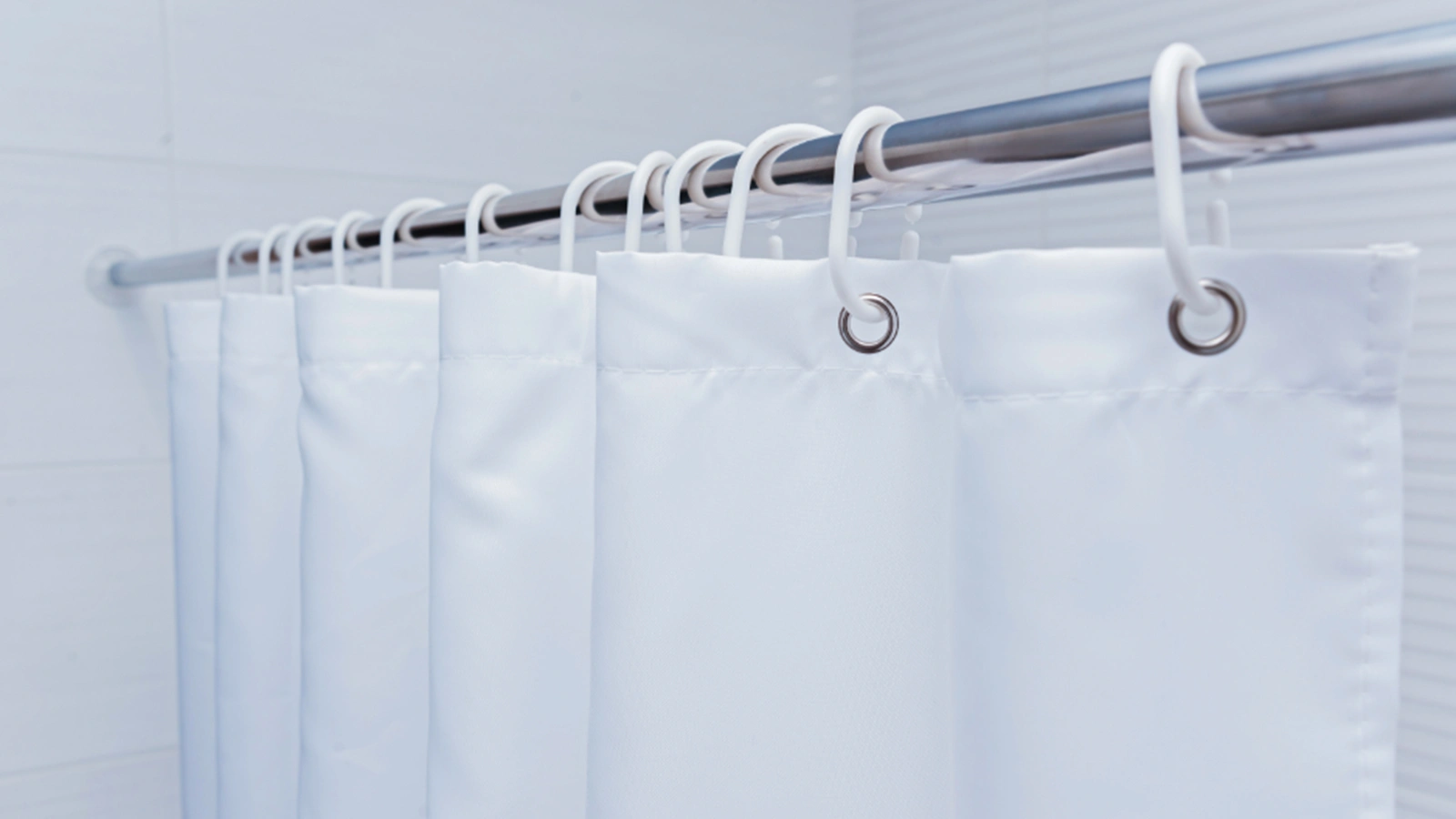 Types of Shower Curtain Hooks: A white shower curtain hanging on a hook in a bathroom.