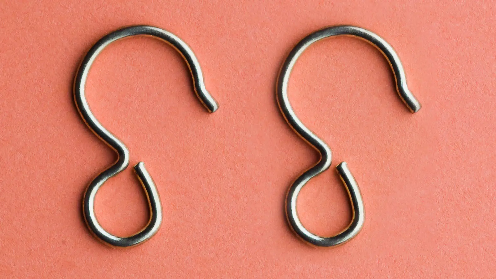 Types of Shower Curtain Hooks: Two metal hooks on a pink background.