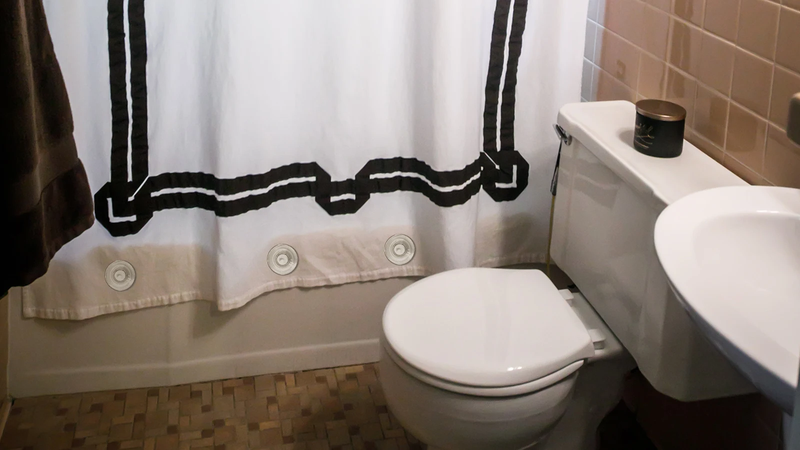 A bathroom with a black and white shower curtain that demonstrates how keeping the shower curtain closed effectively improves privacy and prevents water from splashing onto the floor.