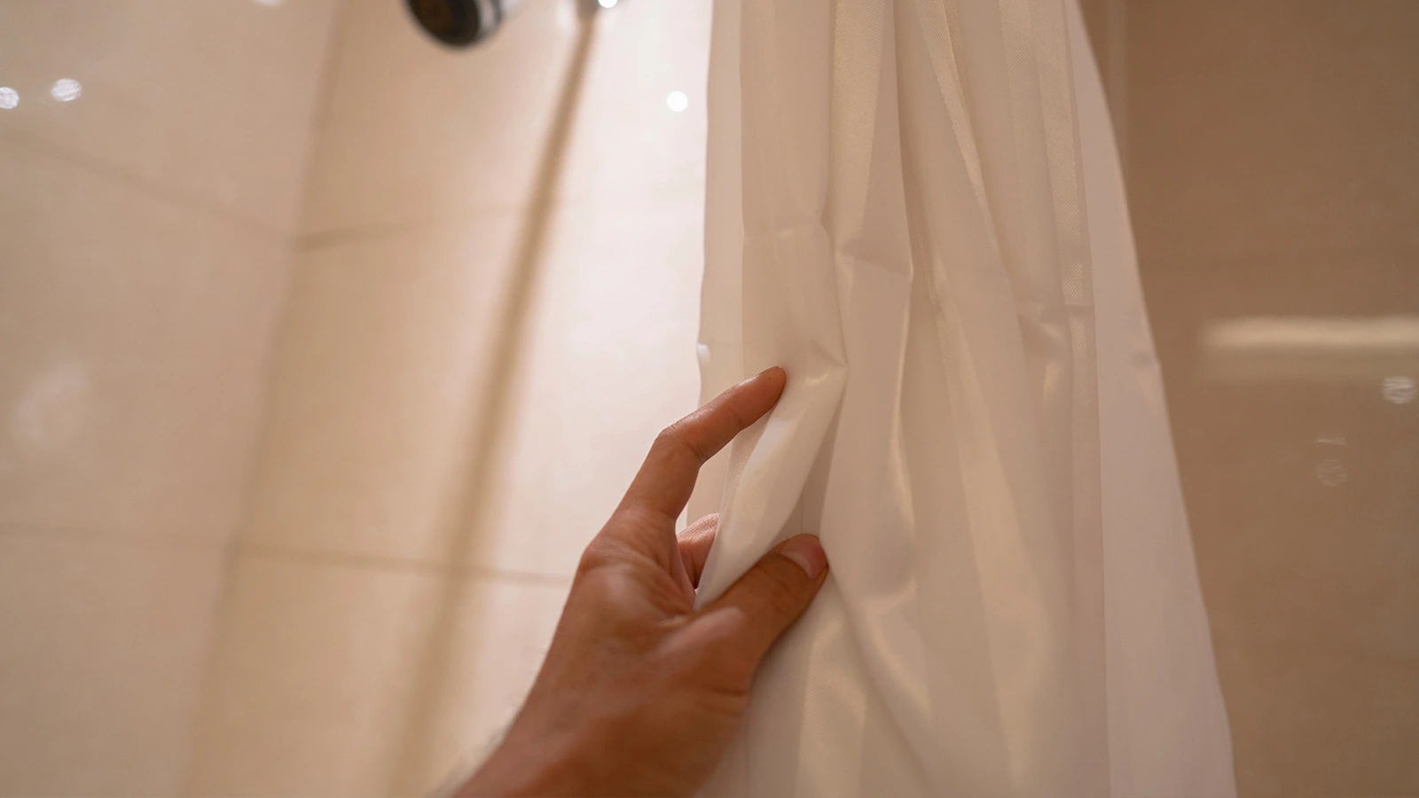 A person holding a white shower curtain and demonstrating how to keep it closed effectively.